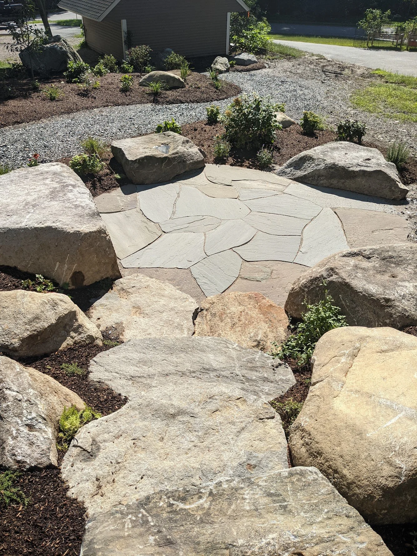 Flagstone patio surrounded by large boulders and mulched garden beds